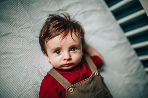 Free High angle of hairy baby with blue eyes in stylish outfit lying in crib Stock Photo