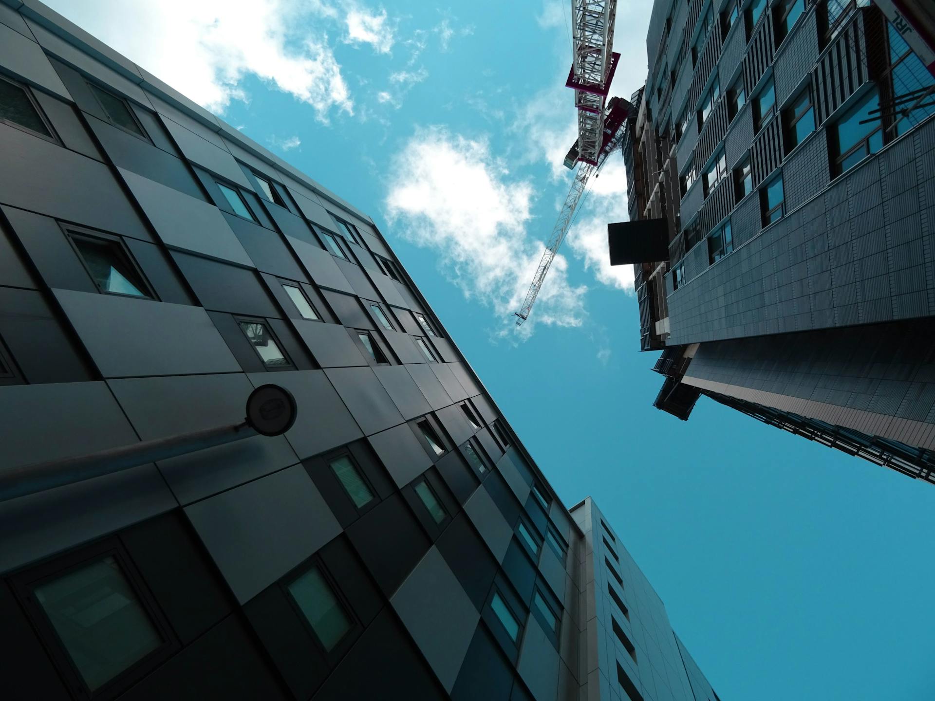 Modern skyscrapers and a construction crane against a bright blue sky, showcasing contemporary urban architecture.