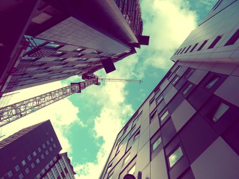 A captivating view of modern skyscrapers and a crane against a bright sky.