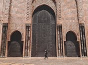 Side view unrecognizable person walking on piled steps of ornamental impressive mosque entrance in oriental style