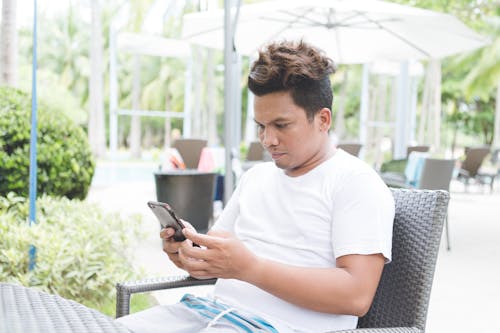 Focused man browsing smartphone in outdoors cafe