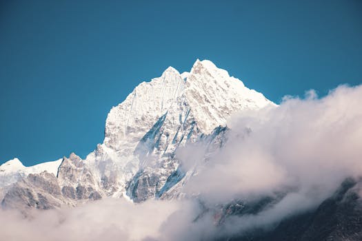 Majestic view of a snow-covered mountain peak enveloped in clouds, showcasing natural beauty and tranquility.