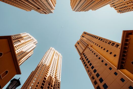 Low-angle view of Dubai skyscrapers against a clear blue sky, highlighting architectural design.