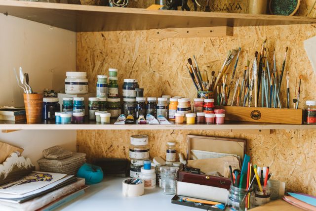 An artist workspace filled with paints and brushes — photo by Yaroslav Shuraev on Pexels