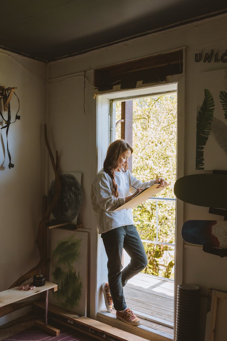 A Woman Drawing While Standing Beside The Door 