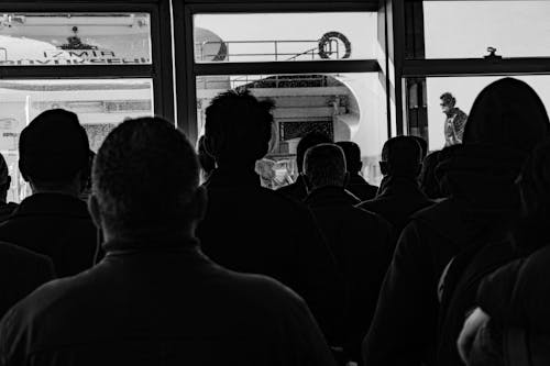 Grayscale Photo of People Standing beside Glass Door