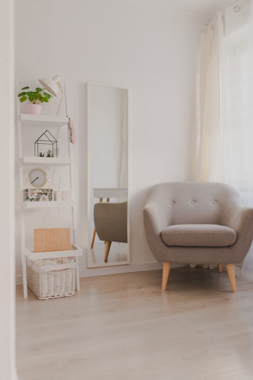 Free Armchair near mirror and shelves in minimalist room Stock Photo