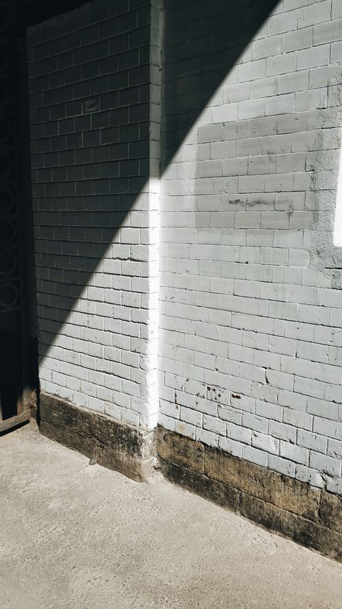 Free Sunlit corner of a textured brick wall displaying an urban aesthetic, contrasting shadows add depth. Stock Photo
