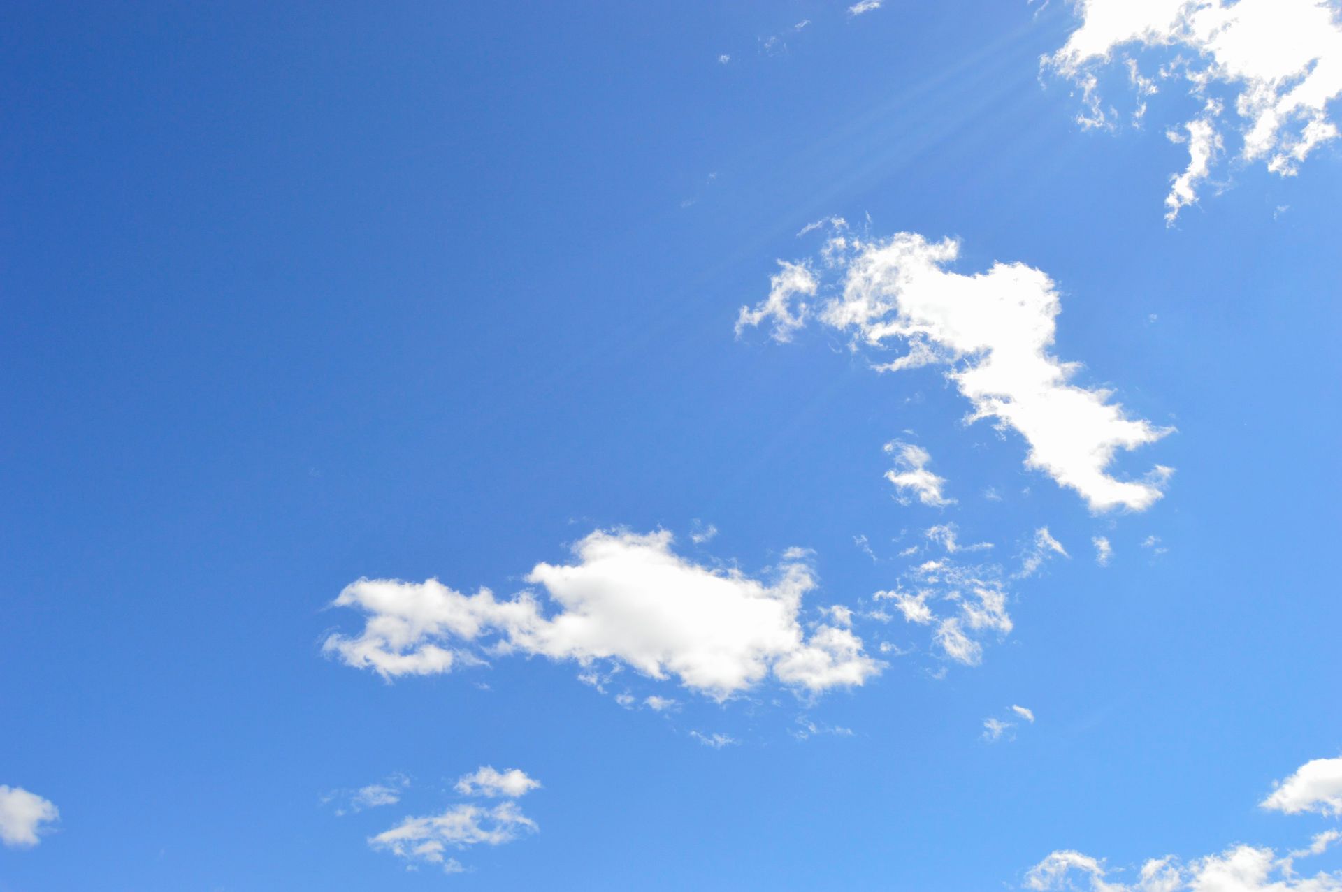 A clear blue sky with scattered white clouds on a bright day, perfect for backgrounds.