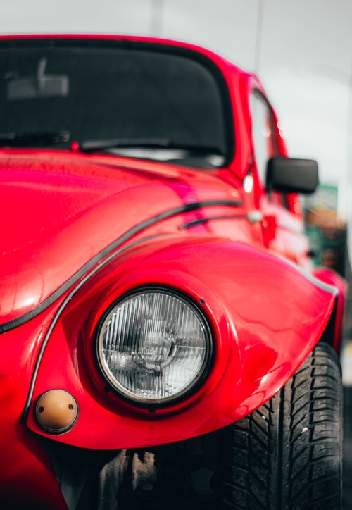 Free A detailed close-up of a vintage red car's headlight and hood, capturing its classic design. Stock Photo