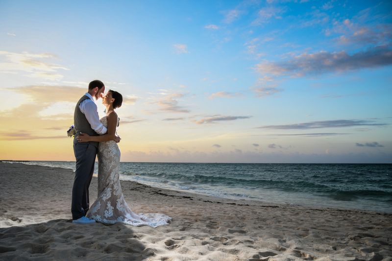 Bride and groom walking along St Kilda Pier at sunset with Melbourne skyline in the distance