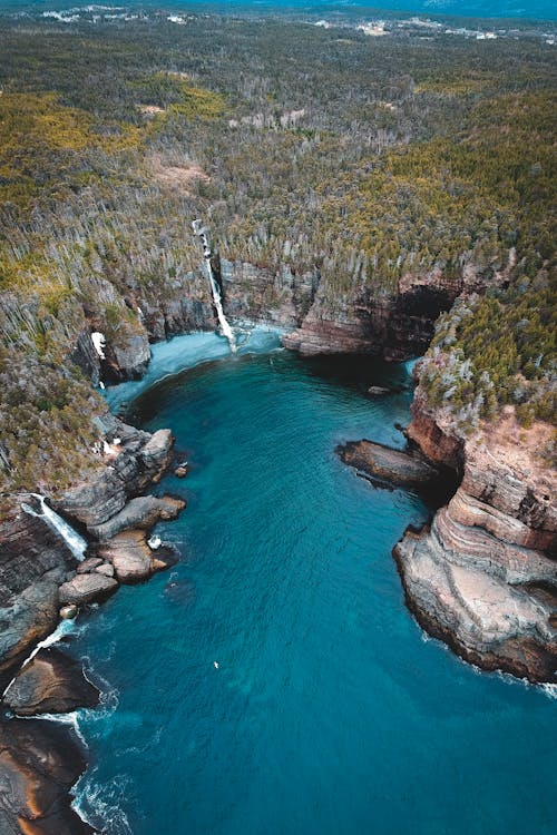 Breathtaking aerial view of turquoise lagoon surrounded by rocky cliffs with caves and waterfalls