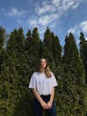 一名年轻女子置身户外，绿树环绕，蓝天清澈，享受着宁静的时刻