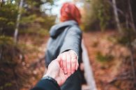 Faceless woman leading boyfriend through autumn forest