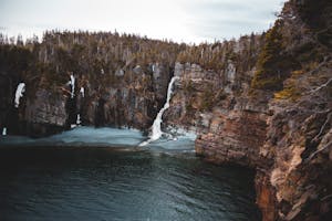 Spectacular scenery of rough mountain formation with rapid splashing waterfall flowing into calm lake