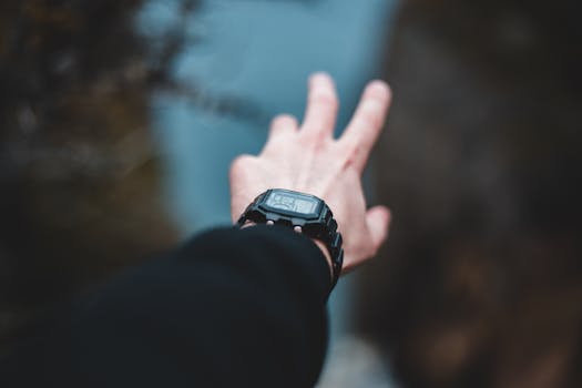A hand wearing a digital wristwatch extends into a serene natural setting, evoking adventure.