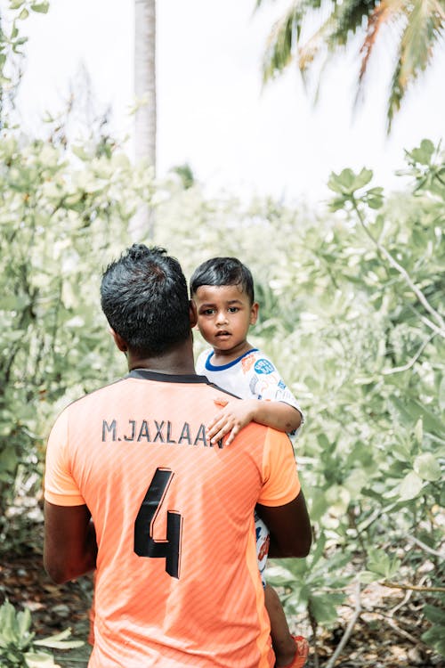 Asian father holding cute son on hands in garden