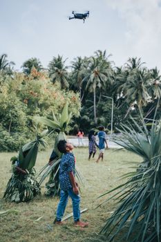 Children enjoy flying a drone in a lush tropical field in Maldives.