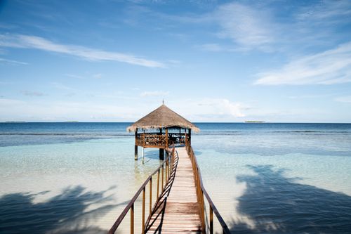 Free Scenic view of a boardwalk leading to a nipa hut over crystal clear waters in the Maldives. Stock Photo