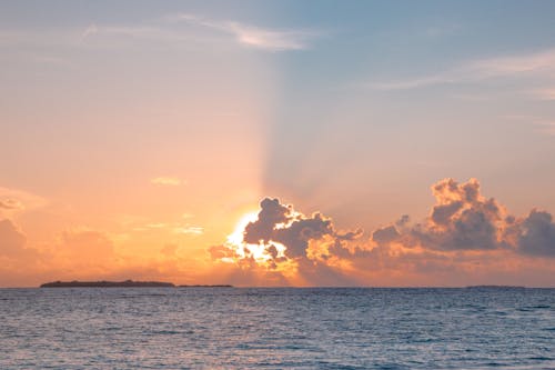 Cloudy sky above ocean at bright sunset