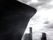 黑白图像中，现代摩天大楼和建筑矗立在戏剧性的多云天空下