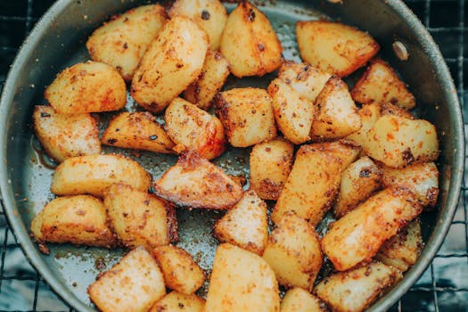 Golden roasted potatoes seasoned to perfection in a frying pan. Ideal for culinary presentations.