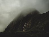 薄雾和乌云笼罩着宁静的山地，隐藏的瀑布从山坡上倾泻而下