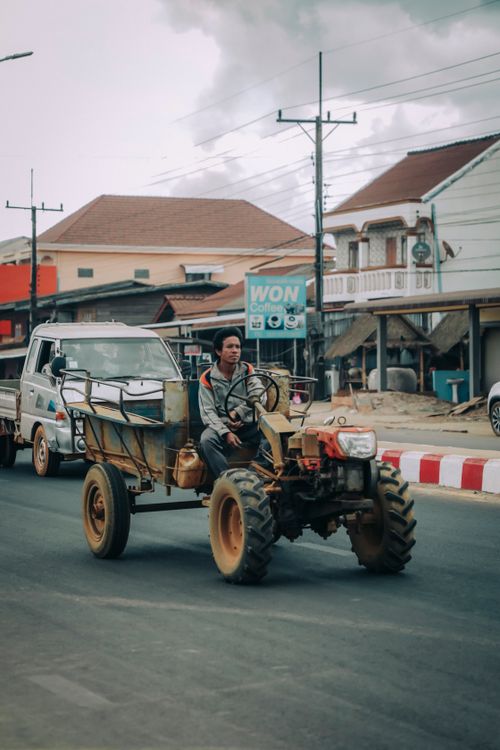 Free Ethnic male driver driving aged ATV on asphalt road near houses in city under cloudy sky Stock Photo