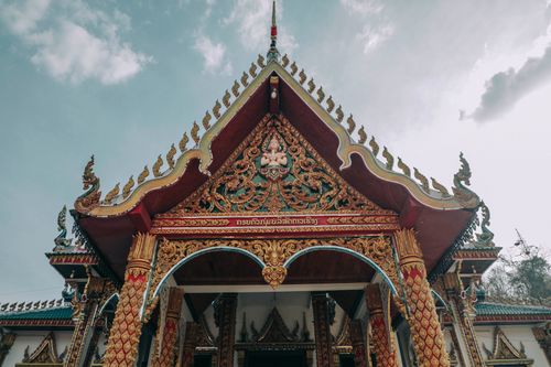 Free From below of ancient masonry Asian temple facade with ornament on roof and arched entrance under cloudy sky Stock Photo