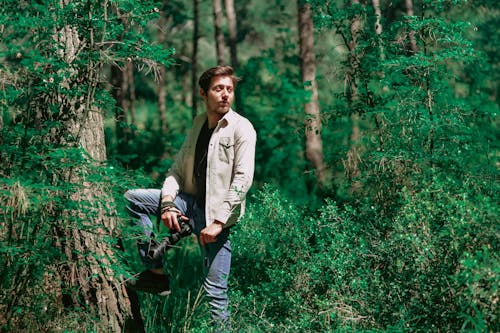 Dreamy ethnic photographer with photo camera in forest