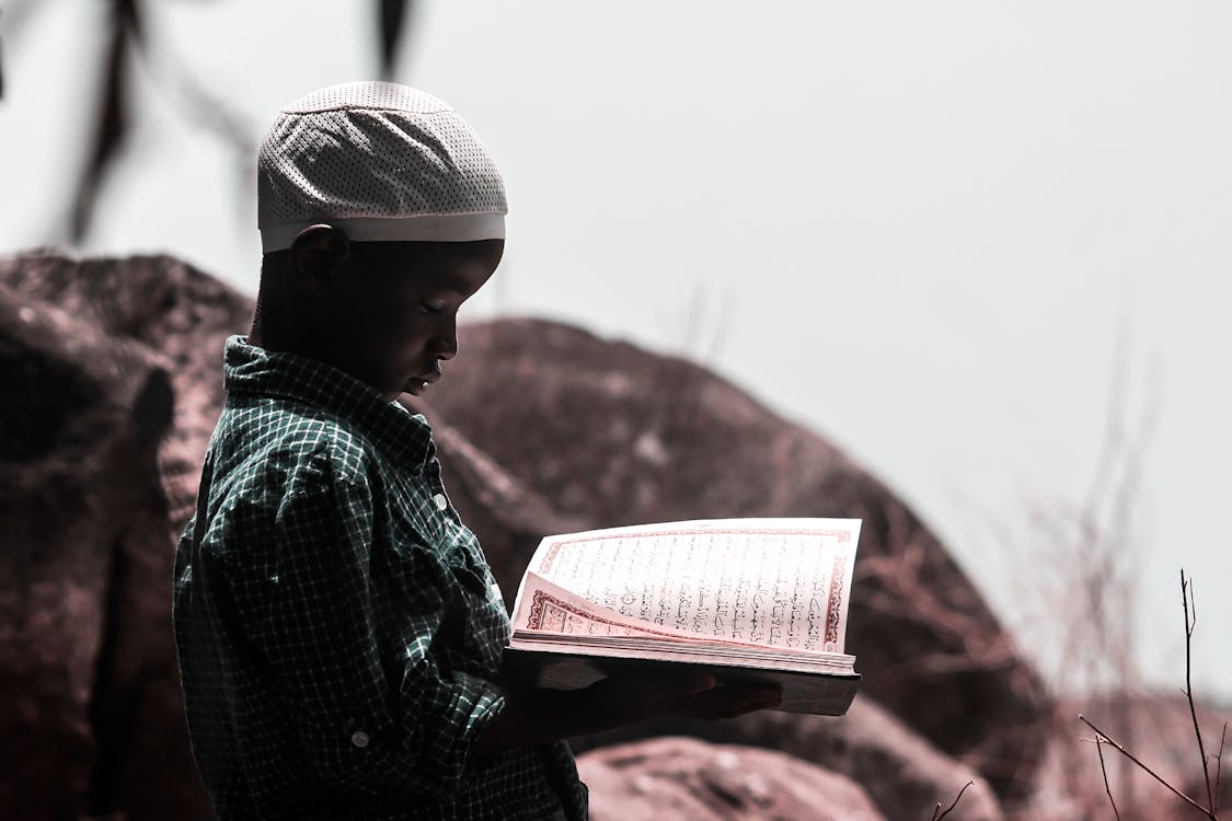 Photo Of Boy Holding Religious Book