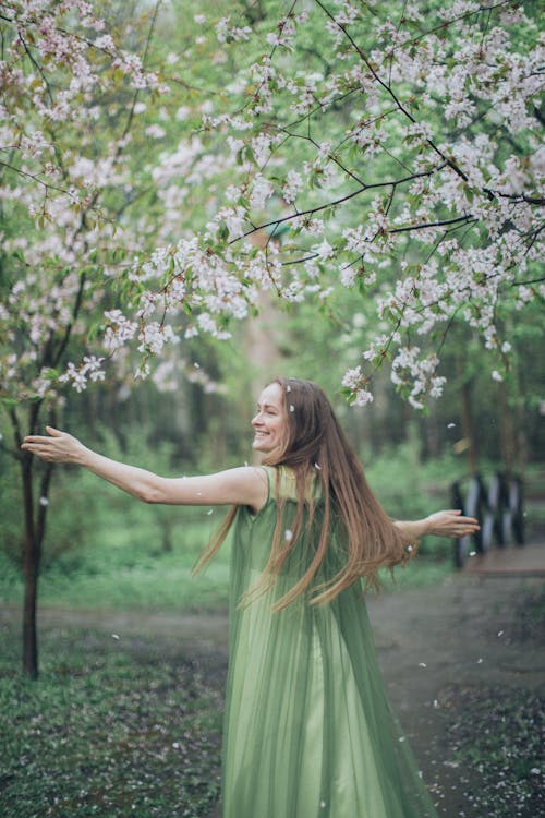 Woman in Green Dress Standing Under White Petaled Flowers