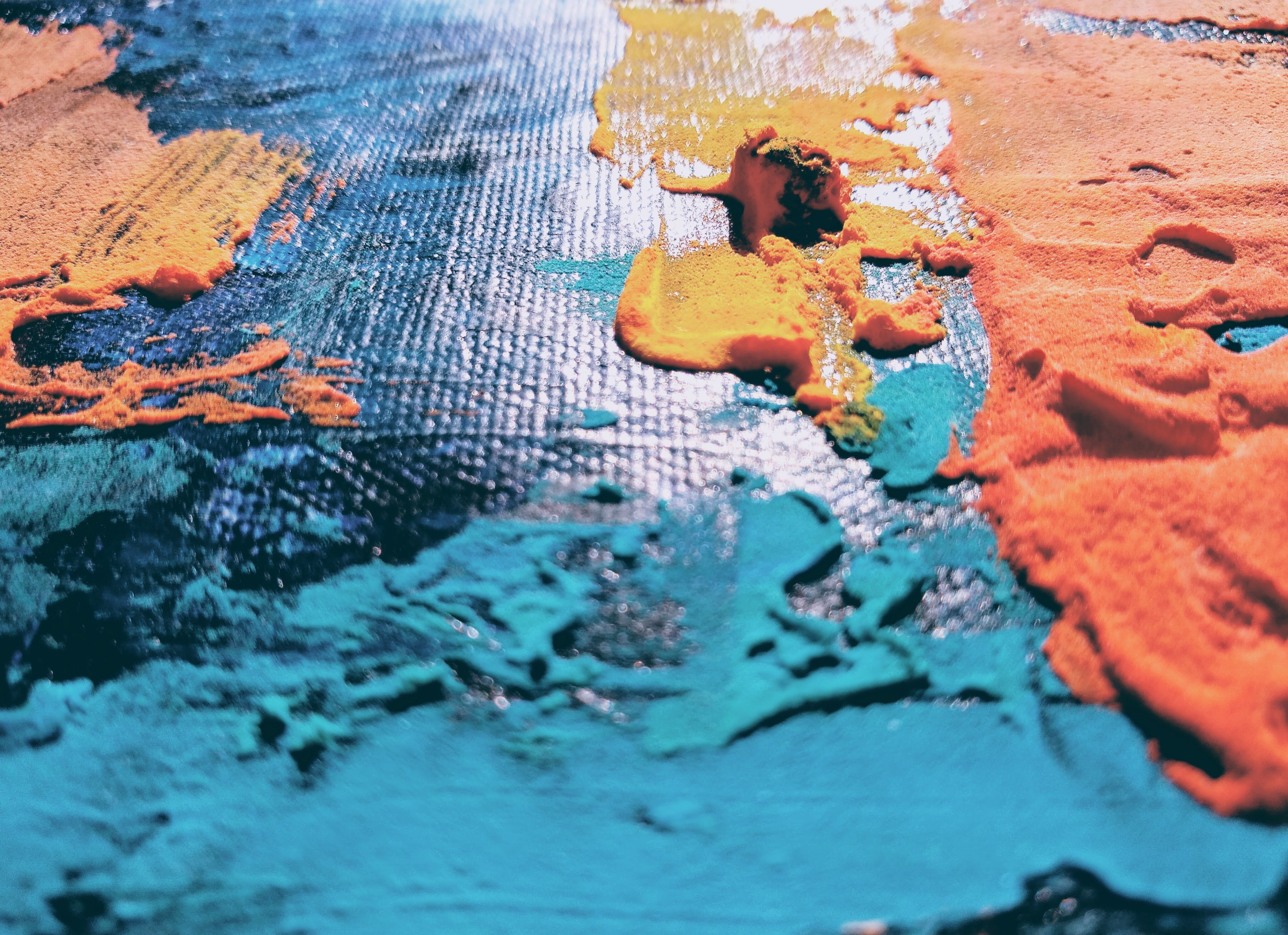 Close-up view of vibrant colored paints on a surface, showcasing an abstract texture.