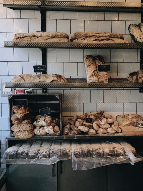 Freshly baked artisan breads neatly displayed on metal shelves in a London bakery.