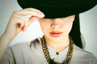 Crop stylish woman in hat and necklace on white background