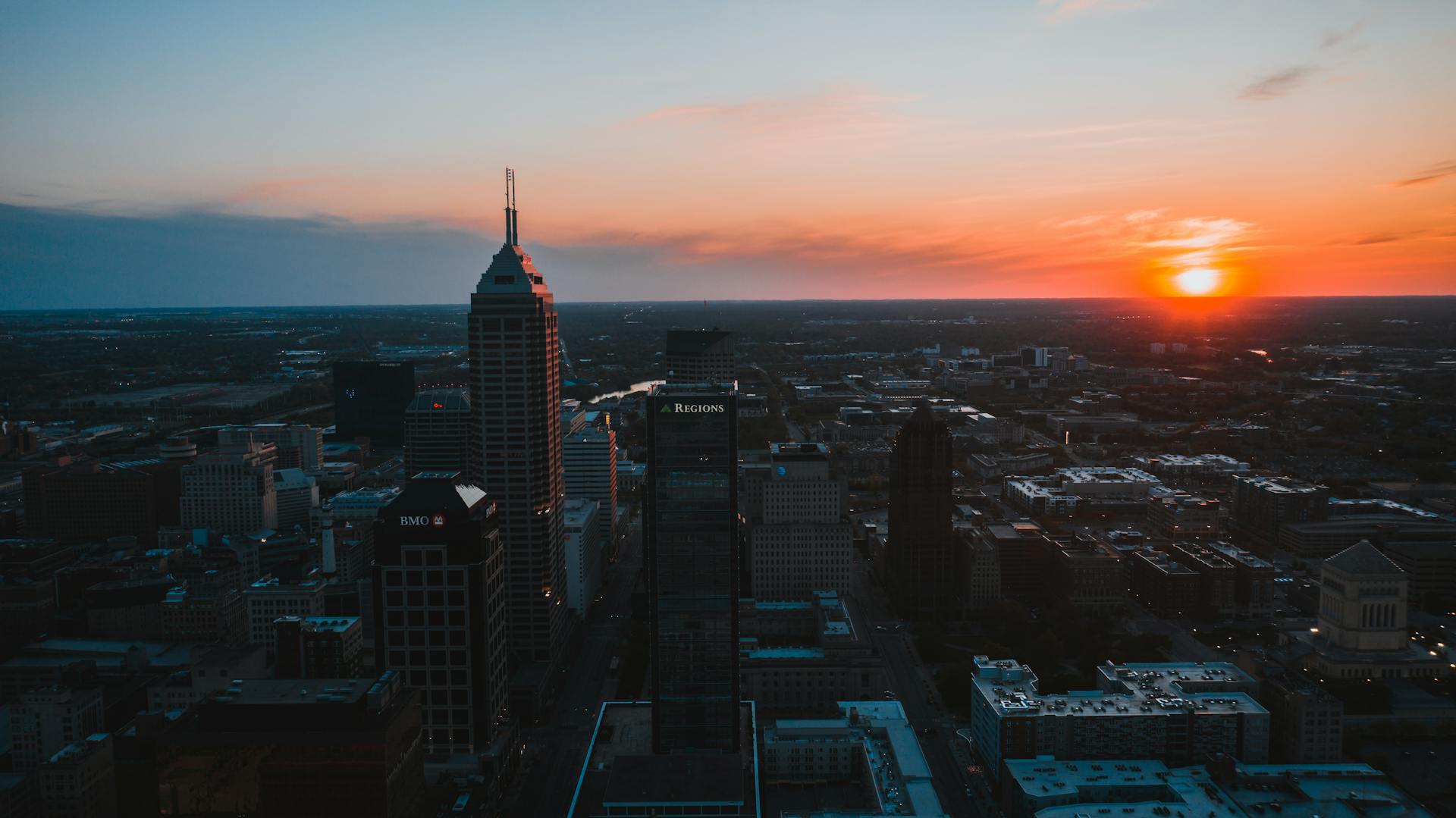Aerial view of Indianapolis skyline at sunset with vibrant colors and urban landscape.