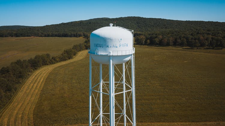 Water Tower In Green Field Behind Mountain