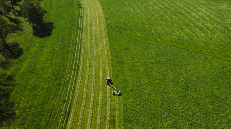 Aerial View Of Tractor Landscape Rake On Green Grass Field