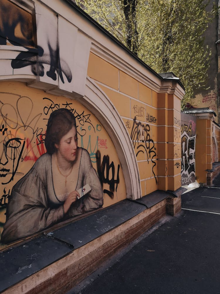 A Mural And Grafitti On A Brick And Concrete Fence