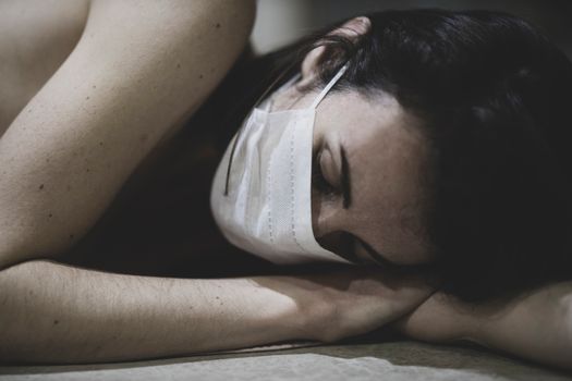 一位戴着口罩、脸上有雀斑的妇女在室内睡觉，象征着疲劳与康复
