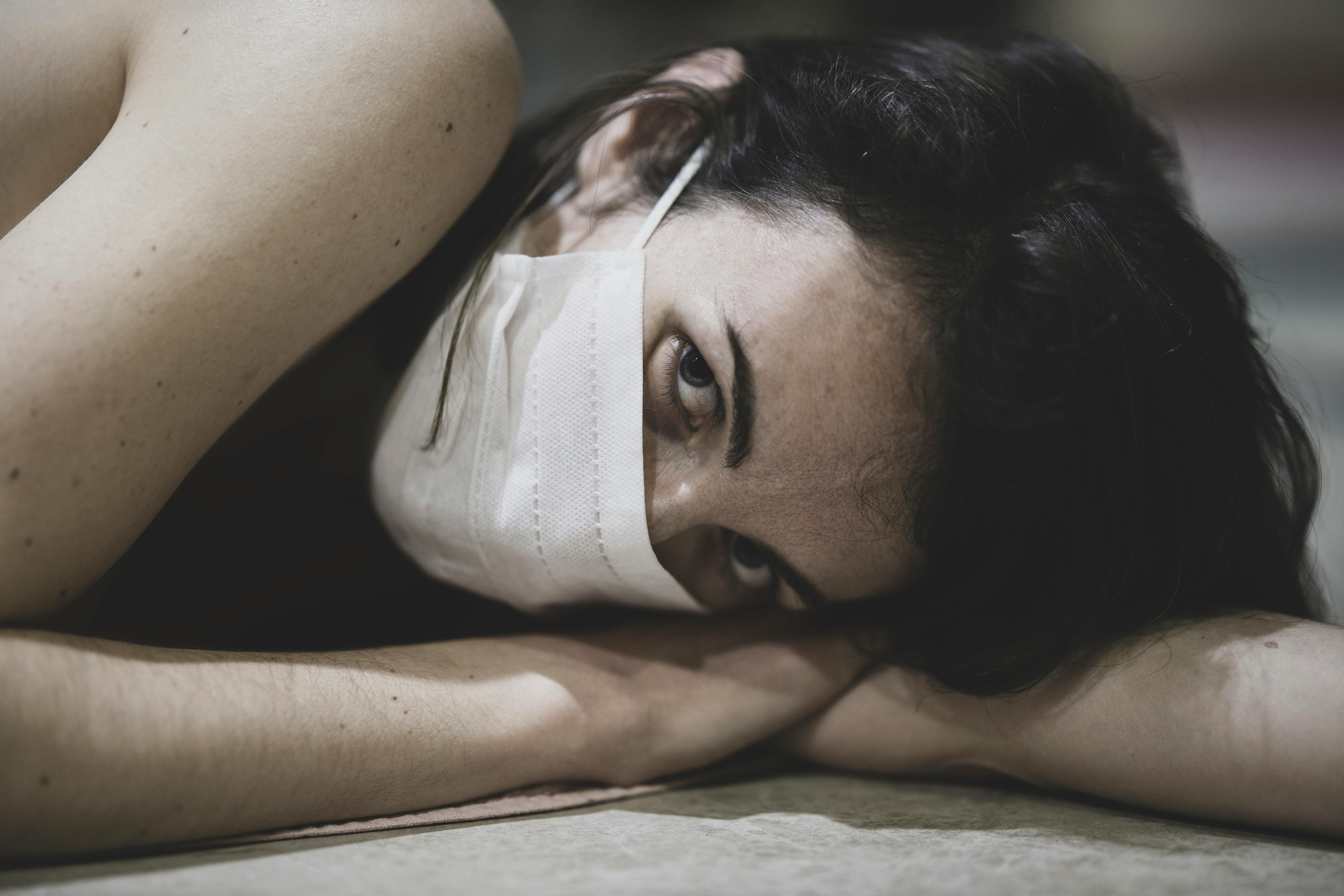 Woman in White Face Mask Lying on a Floor