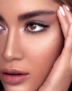 Elegant close-up of a woman's face with shimmering eye makeup and glossy lips.