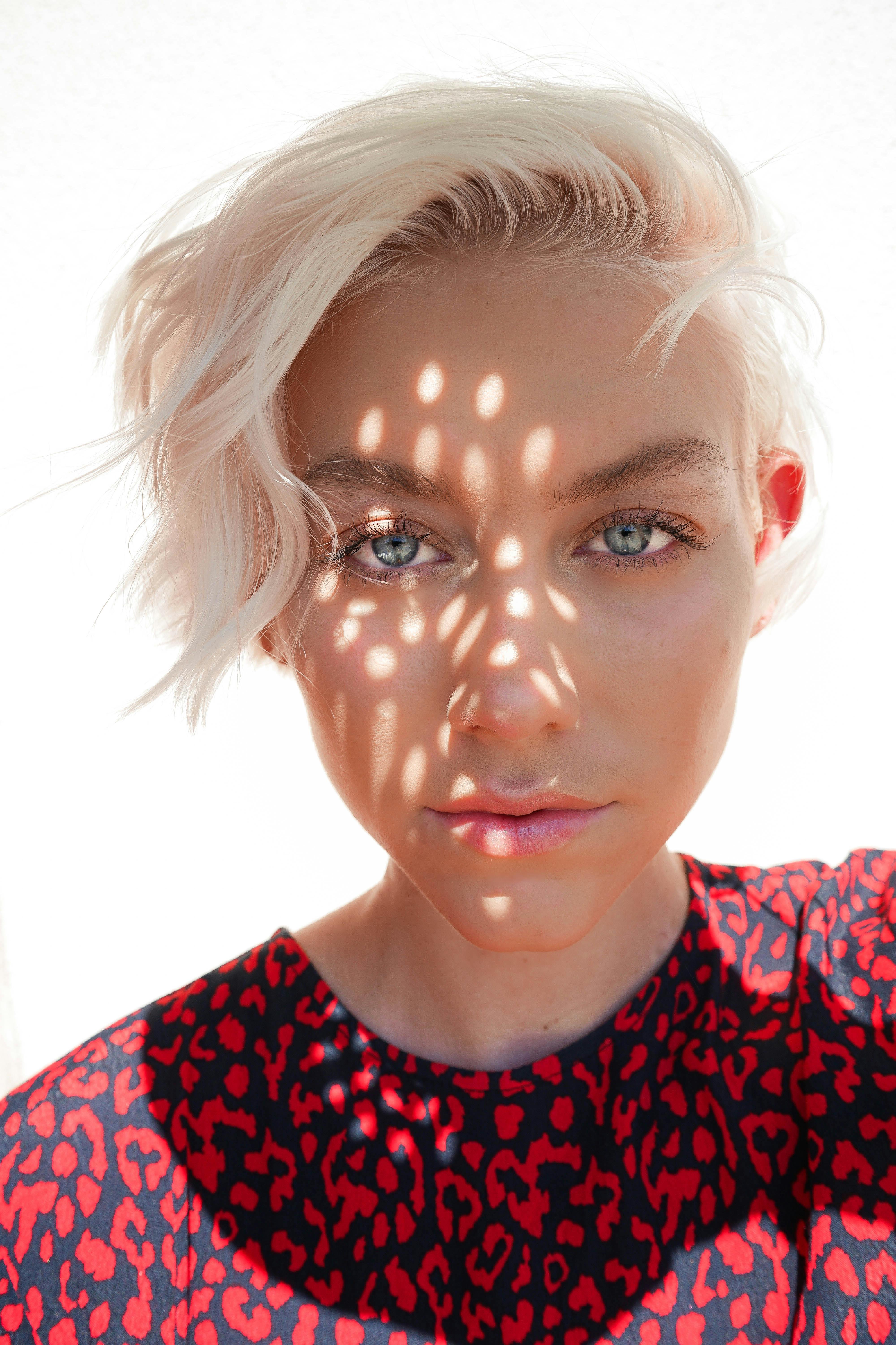 Close-up portrait of a woman with artistic light and shadow patterns on her face.