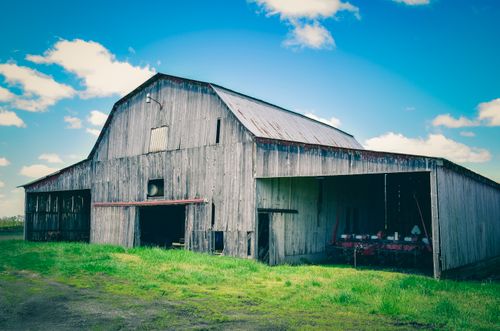 Free From below of aged wooden construction near green lawn under bright blue cloudy sky in countryside Stock Photo