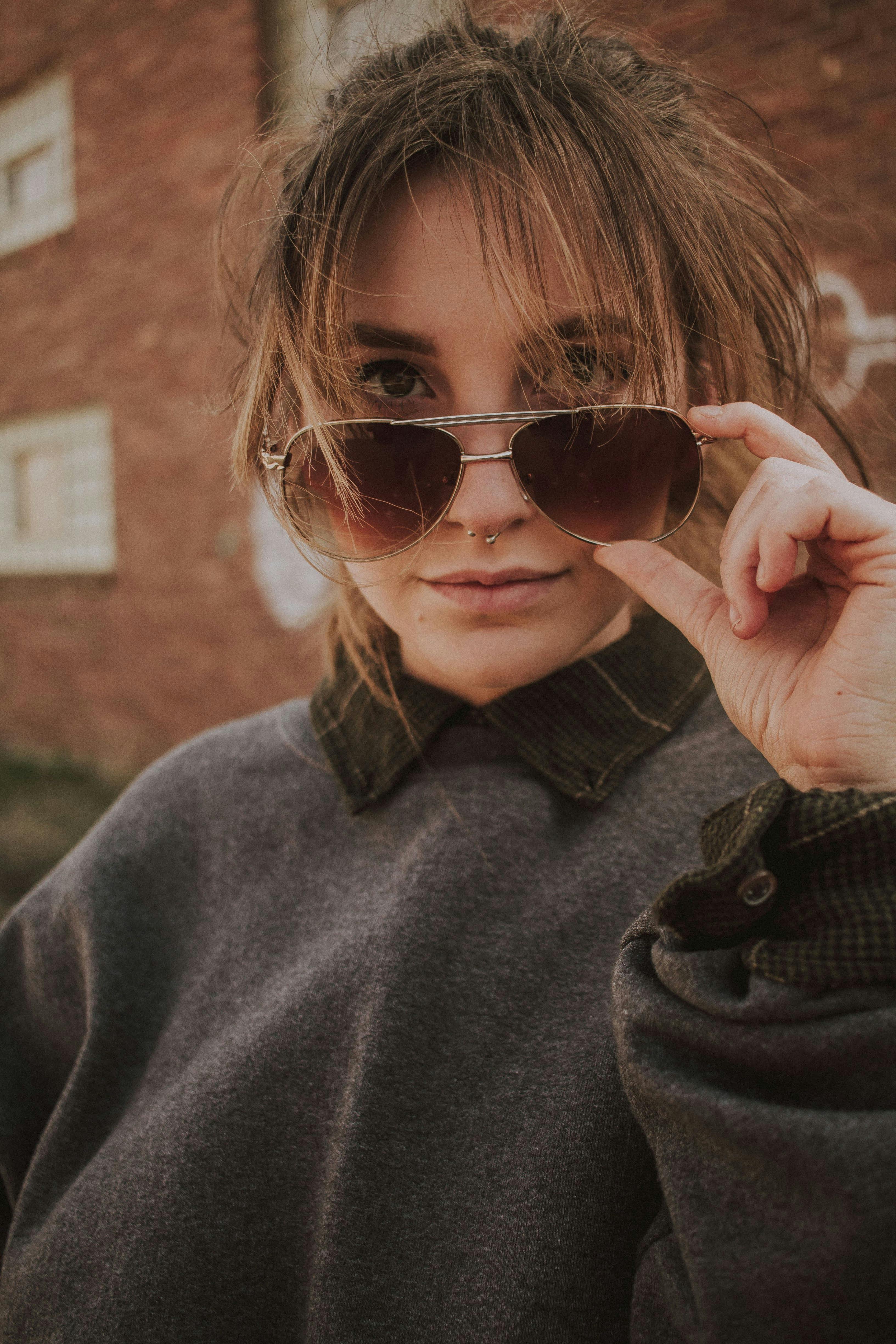 trendy woman in sunglasses near building wall on street