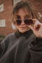 Trendy woman in sunglasses near building wall on street