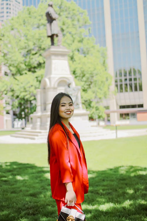 Photo of Woman in Red Blazer Standing on Grass Field