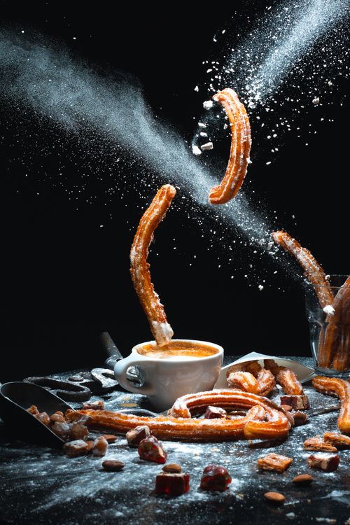 Free Creative studio shot of churros flying with coffee and powdered sugar splash. Stock Photo