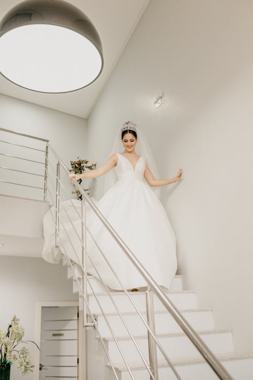 Happy bride in white dress walking down stairs