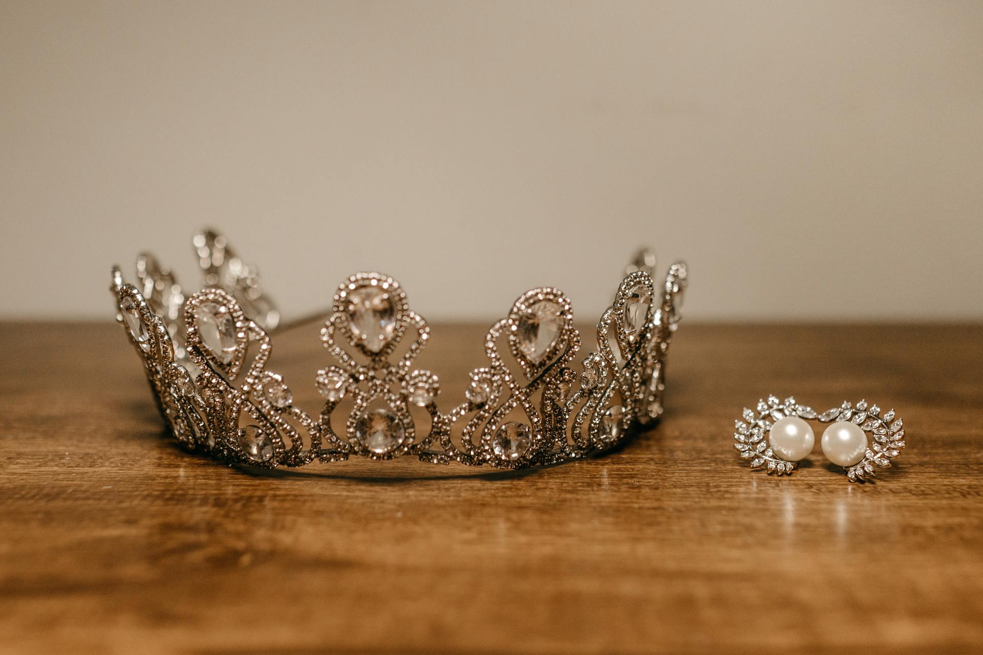 Exquisite diamond crown and earrings displayed on a wooden surface, showcasing elegance and luxury.